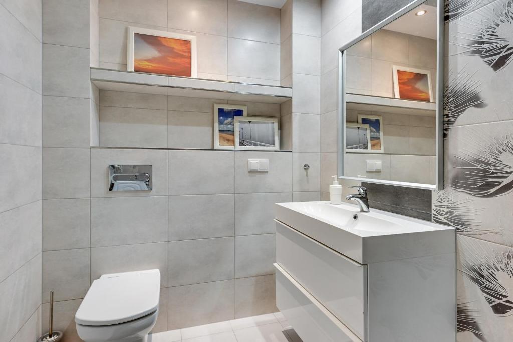 a white bathroom with a toilet and a sink at Grand Apartments - Neptun Park. in Gdańsk