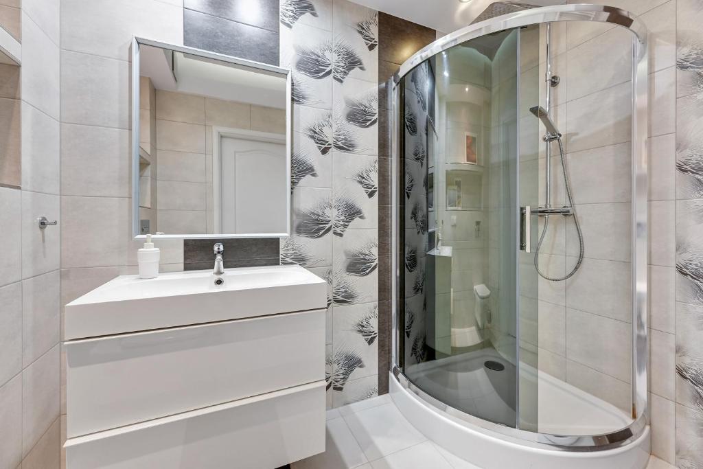 a white bathroom with a sink and a shower at Grand Apartments - Neptun Park. in Gdańsk