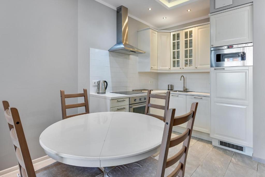 a white kitchen with a white table and chairs at Grand Apartments - Neptun Park. in Gdańsk