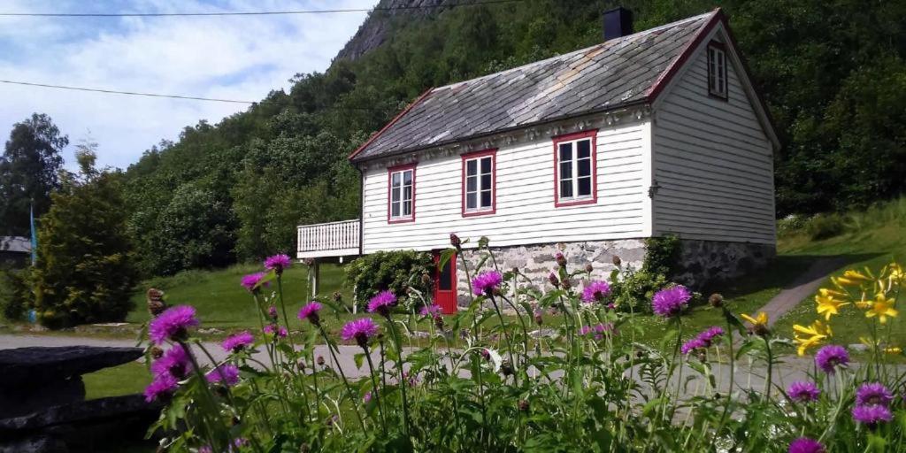 una piccola casa con fiori rosa di fronte di Vollsnes Gjestehus a Stryn