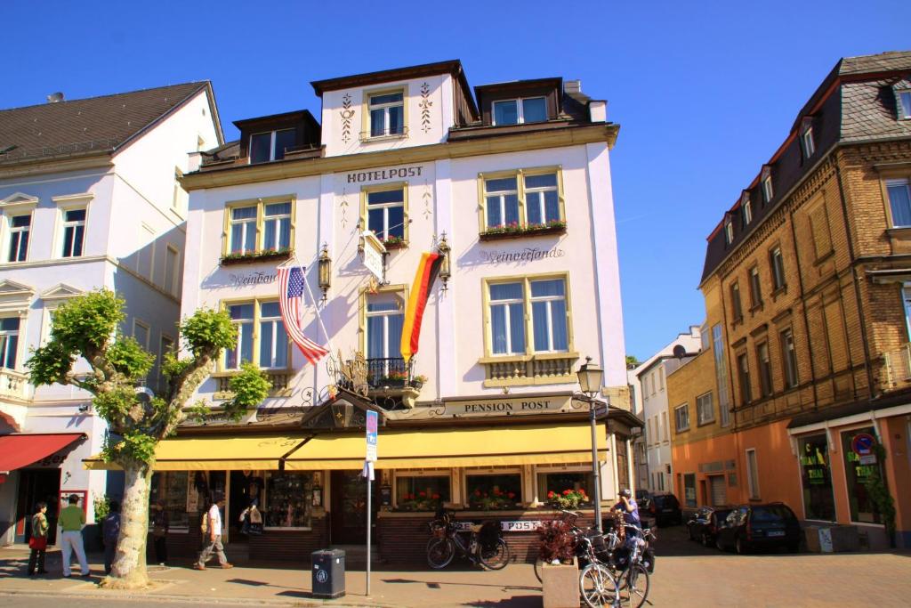 a tall white building on a city street at Pension Post Rüdesheim in Rüdesheim am Rhein