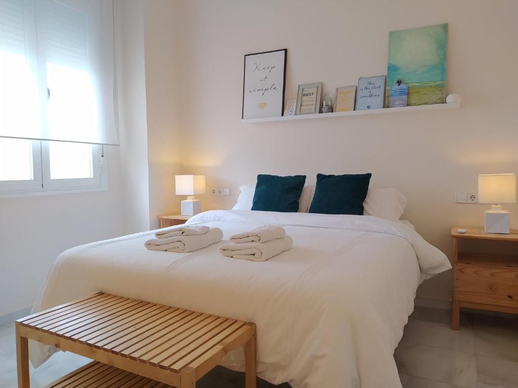 1 dormitorio con 1 cama blanca grande y toallas. en Sherryflat Azahar, en Jerez de la Frontera