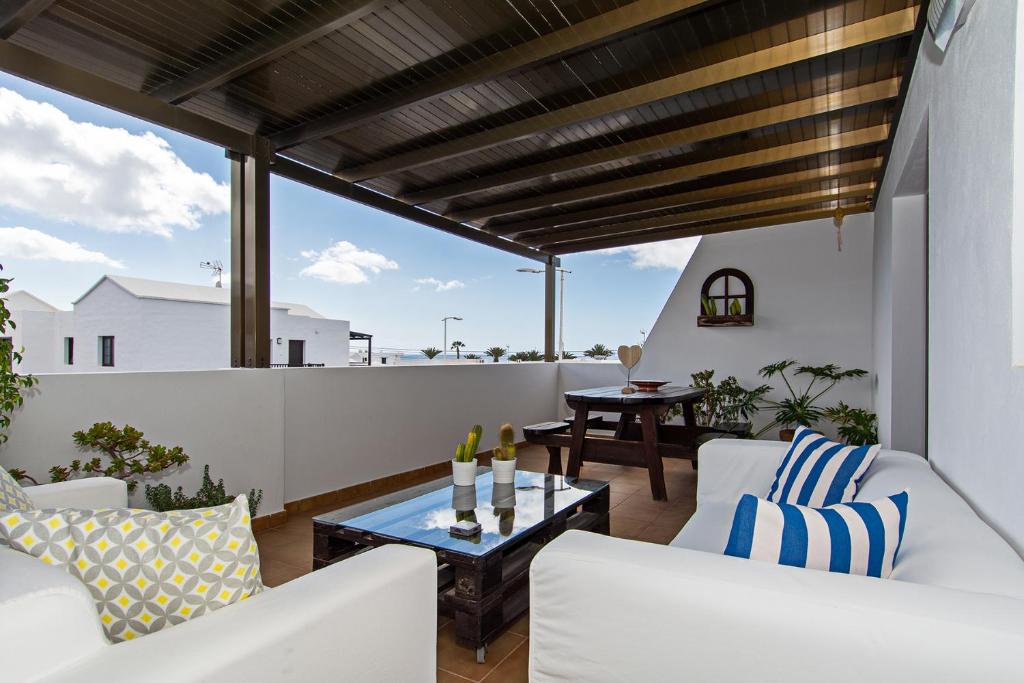 balcón con muebles blancos y mesa de cristal en Apartment Fragata en Playa Honda