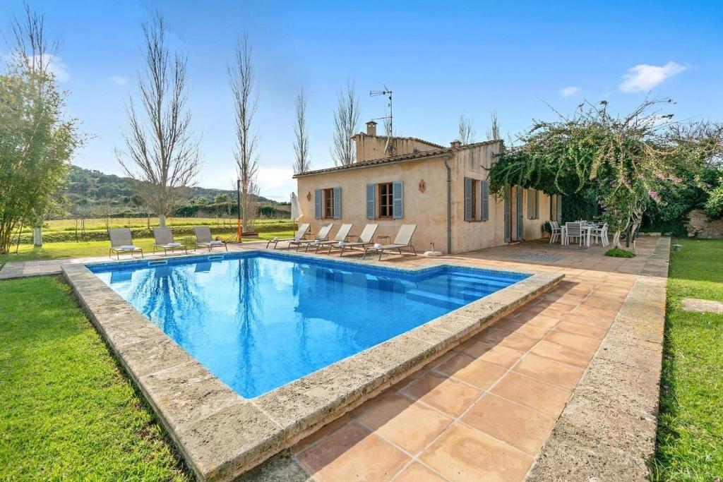 una piscina in un cortile con sedie e una casa di Es Molí de Son Comparet a Son Servera