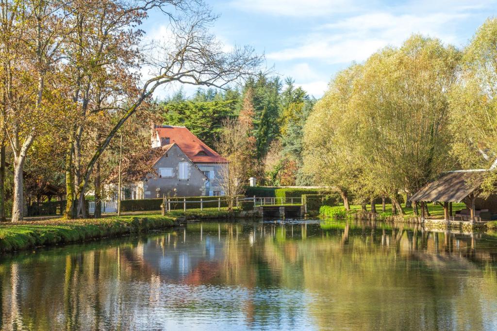 una casa junto a un río con árboles en Le Moulin de Pasnel, en Monteaux