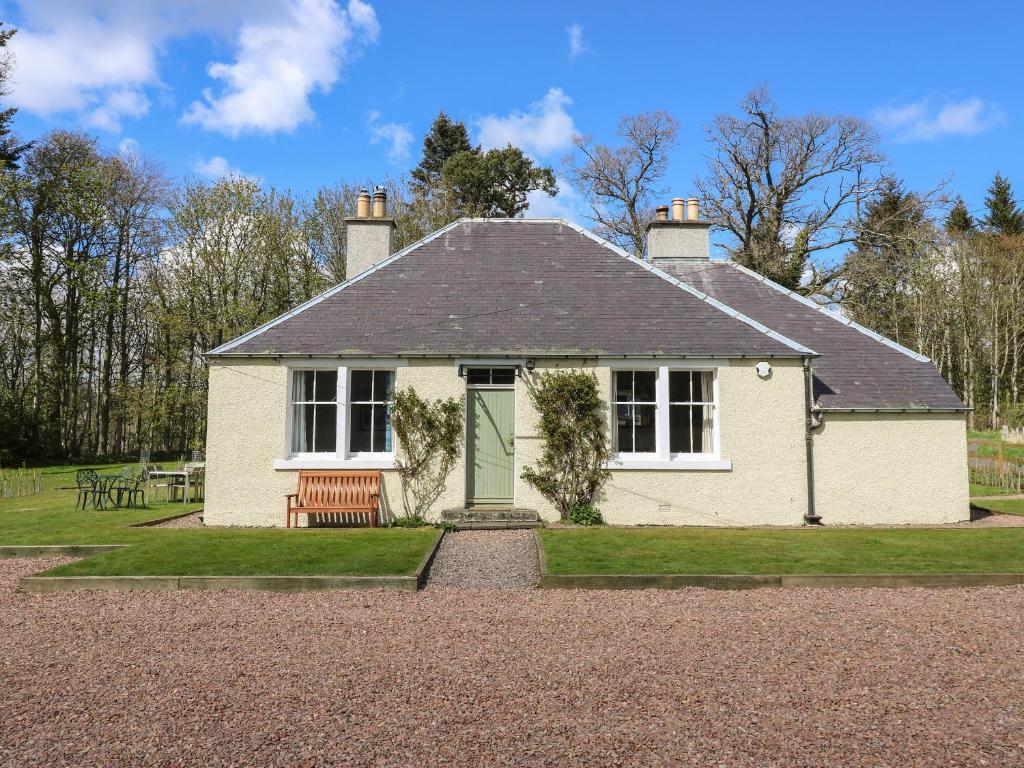 uma casa branca com uma porta verde e um banco em Kirklands Garden House em Melrose