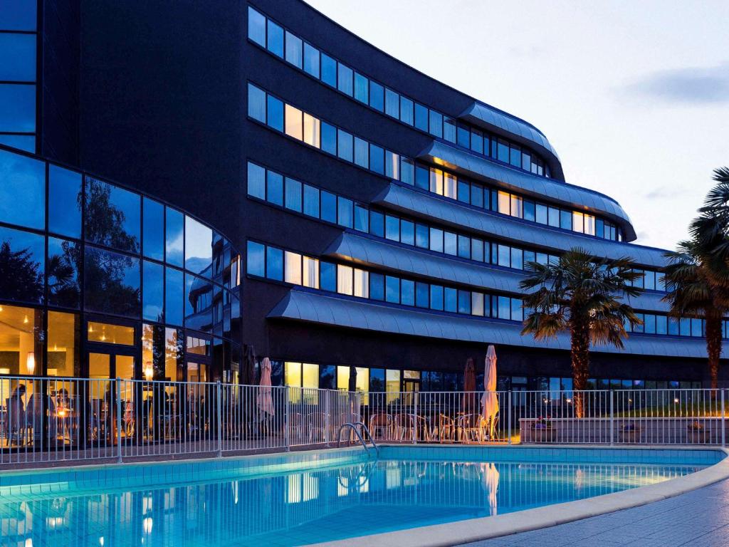 a building with a swimming pool in front of a building at Novotel Poitiers Site du Futuroscope in Chasseneuil-du-Poitou