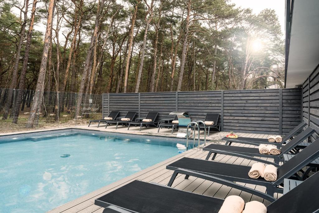 a swimming pool with chairs and a table next to it at Rezydencja Morski Tygiel in Łeba