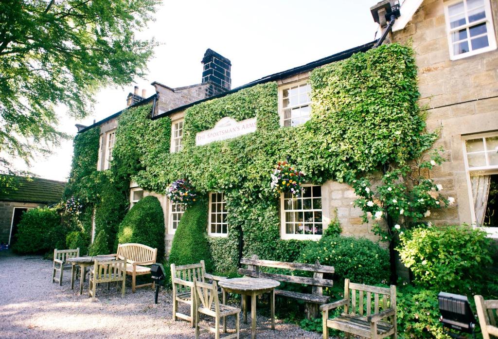 un edificio cubierto de hiedra con mesas y sillas delante de él en The Sportsman's Arms en Harrogate