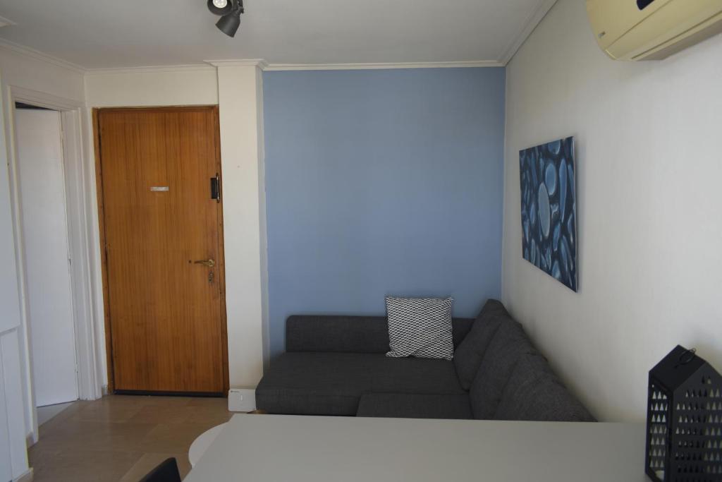 ein Wohnzimmer mit einem Sofa und einer Holztür in der Unterkunft Theo's loft in Athen