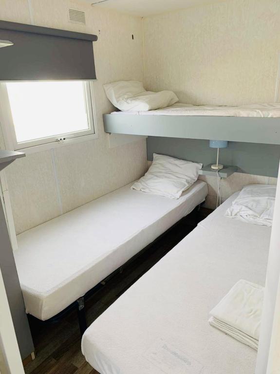 two bunk beds in a small room with a window at Mobil-home 4 personnes 400m de la mer in Berck-sur-Mer