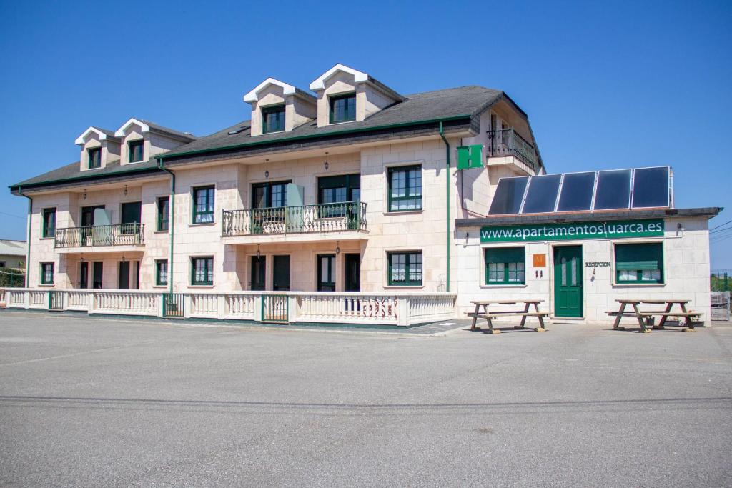 a building with two picnic tables in front of it at Apartamentos Luarca in Luarca