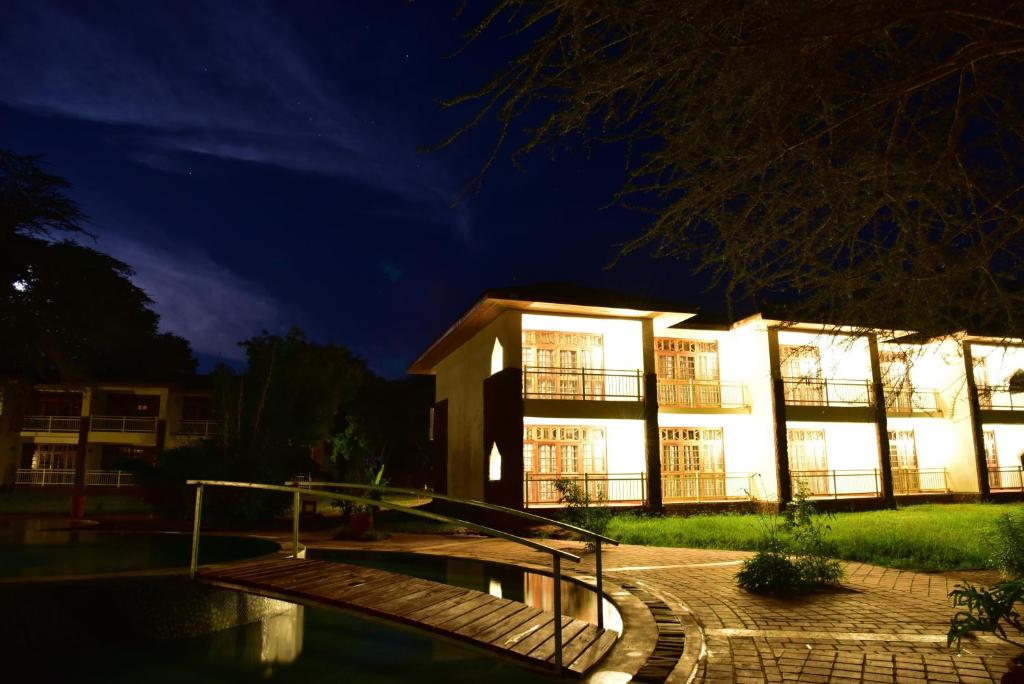 ein Gebäude in der Nacht mit Pool davor in der Unterkunft Hunters Lodge in Twaandu