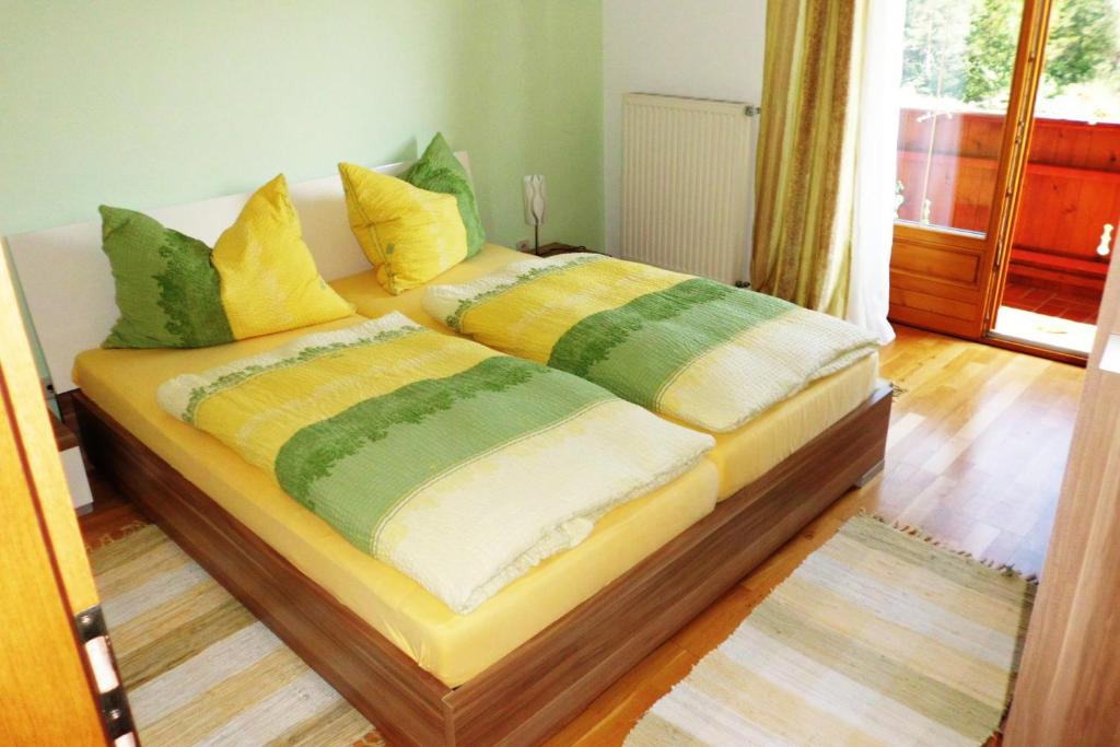 a bed with yellow and green pillows on it at Ferienwohnung Schrittwieser in Faak am See