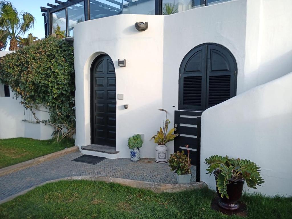 a white house with a black door and some plants at Leilani Cotillo Garden 2 in El Cotillo