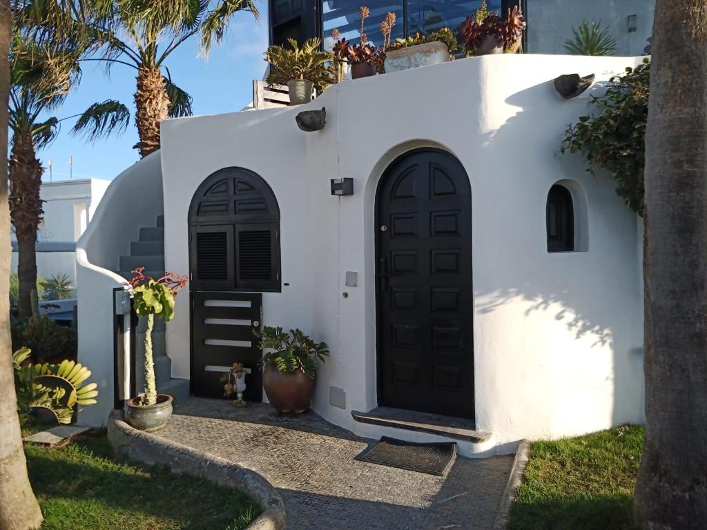 Casa blanca con puertas negras y palmeras en Alana Cotillo Garden 1, en Cotillo