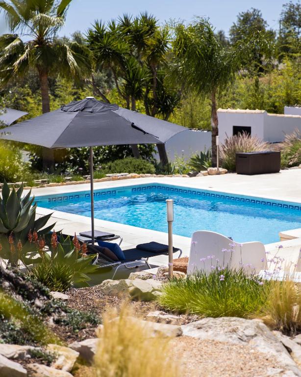 an umbrella and chairs next to a swimming pool at Casa Verdazul in Tavira