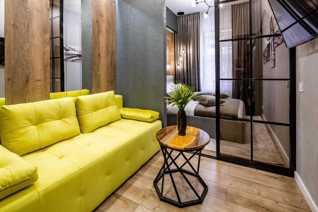 a living room with a yellow couch and a table at Alfa Apartments Kulisha 12 in Lviv