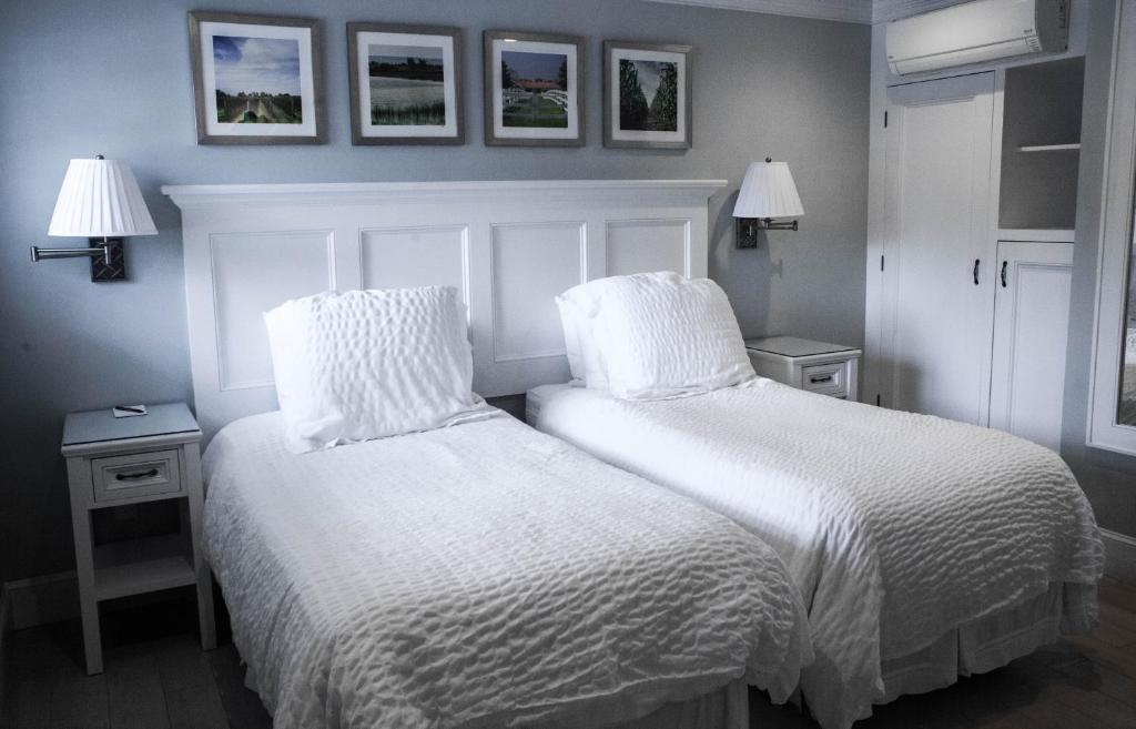 sypialnia z dwoma łóżkami z białą pościelą i obrazami na ścianie w obiekcie Southampton Village Motel w mieście Southampton