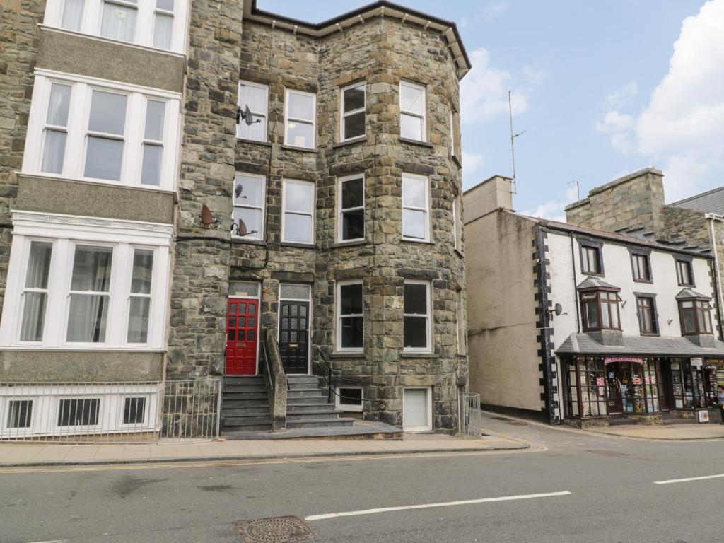 an old stone building with a red door on a street at Sapphire Suite in Barmouth