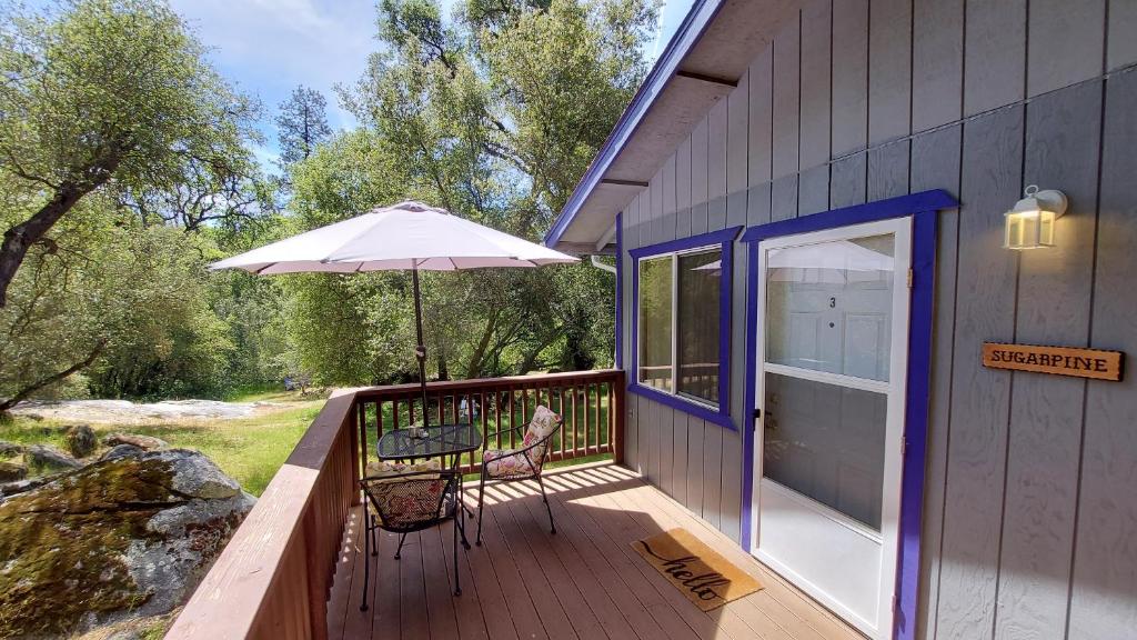 a deck with a table and an umbrella at Little Valley Inn in Mariposa