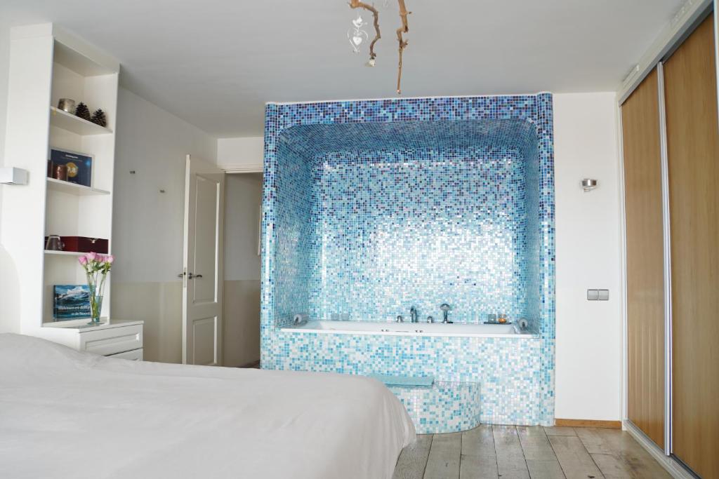 a bedroom with a blue tile wall with a bath tub at Vitamine Zee in IJmuiden
