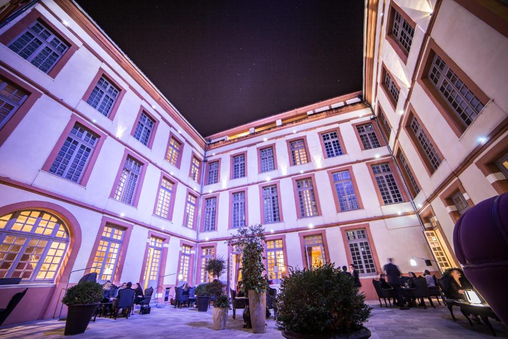 a building with people sitting in chairs in a courtyard at La Cour des Consuls Hotel and Spa Toulouse - MGallery in Toulouse