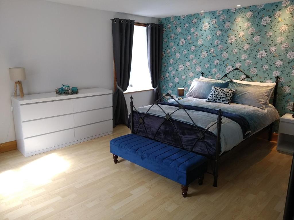 a bedroom with a bed with a blue floral wallpaper at The Old Endie Hoose Kirkwall Orkney in Kirkwall