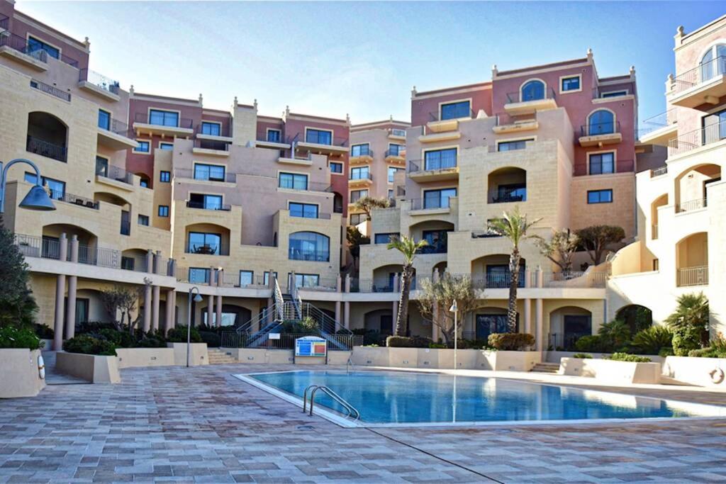 a large apartment complex with a swimming pool in front of a building at Sunny Apartment in Tas-Sellum Mellieha, Malta. in Għajn Żejtuna
