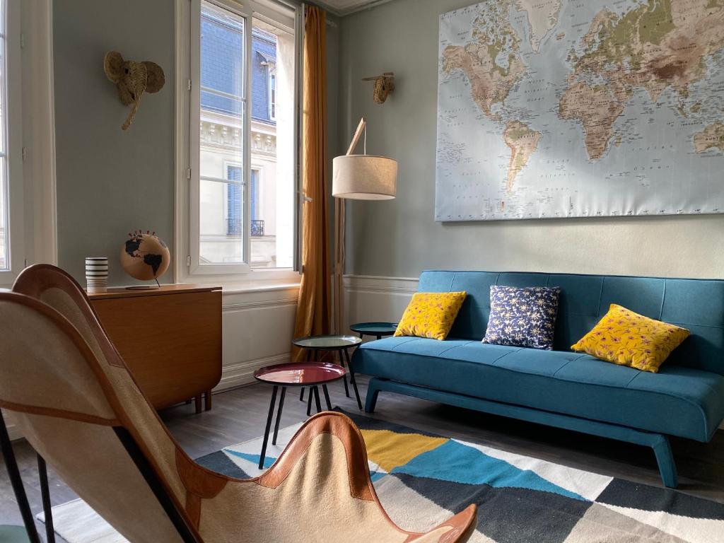 a living room with a blue couch and a map of the world at Le 4B - Le Tiki in Rouen