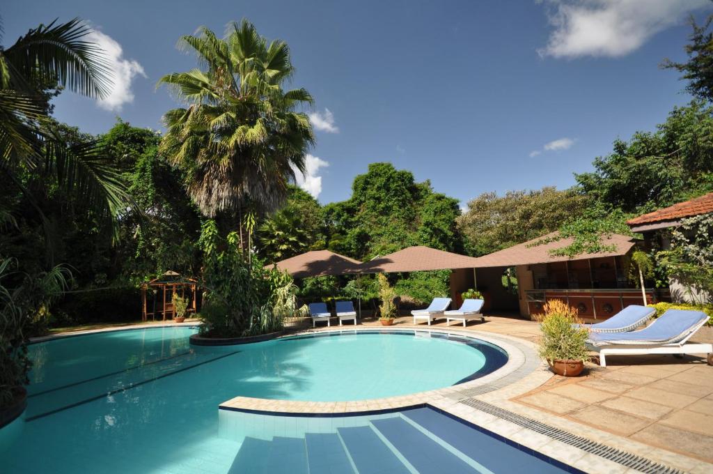 a pool with chairs and umbrellas next to a resort at La Mada Hotel in Nairobi