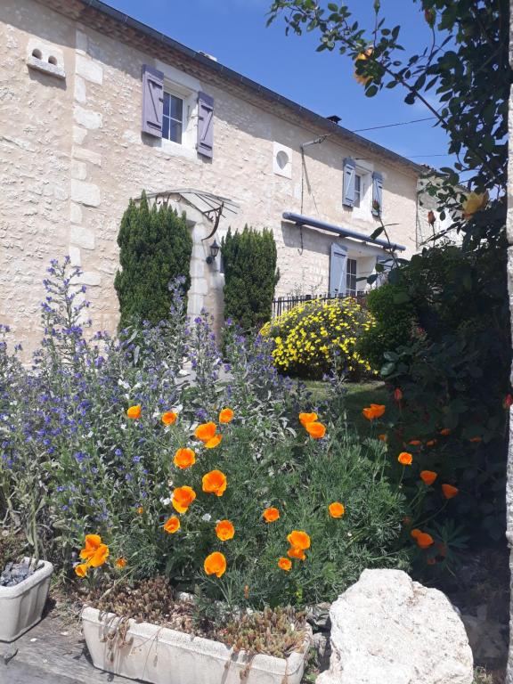 a garden with orange flowers in front of a building at LA MESONNETTA in Soulignonne
