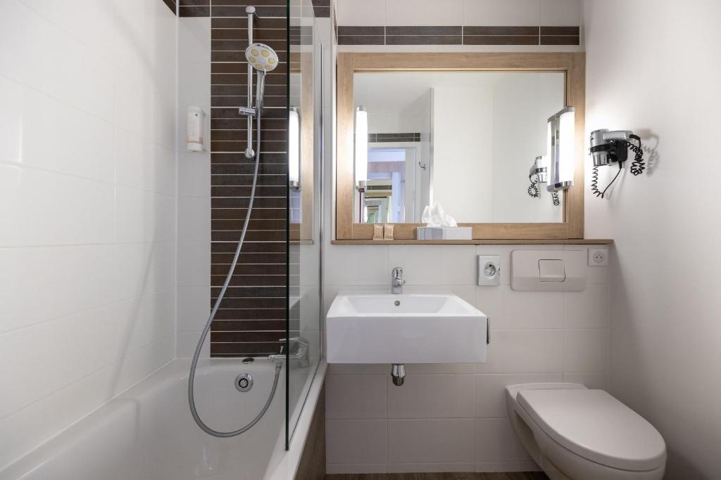 a bathroom with a sink and a toilet and a mirror at Best Western Hotel Le Bordeaux Sud in Gradignan
