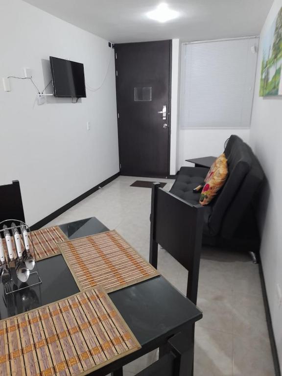 a living room with a black couch and a table at 3'min del Parque del Café Apto y Piscina in Montenegro