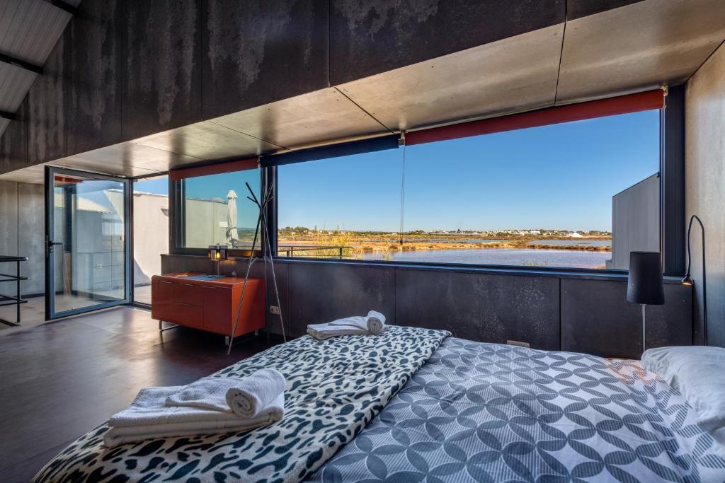 a bedroom with a bed and a large window at The Loft - a birdwatchers paradise in Fuzeta