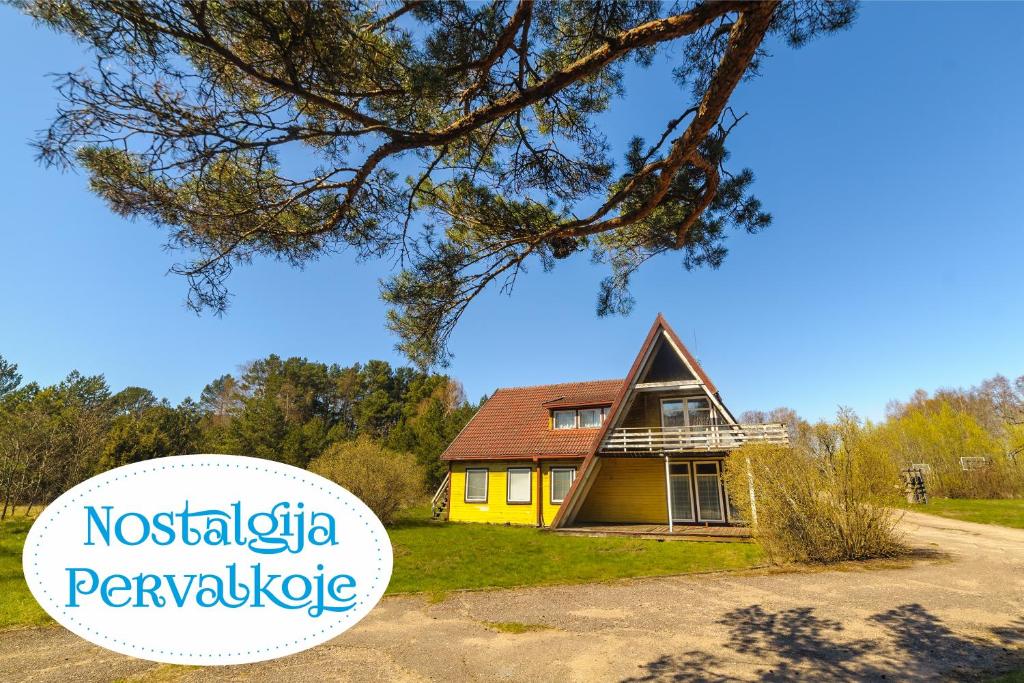 een geel huis met de woorden novaquisticisme paviljoen bij Nostalgija Pervalkoje in Neringa