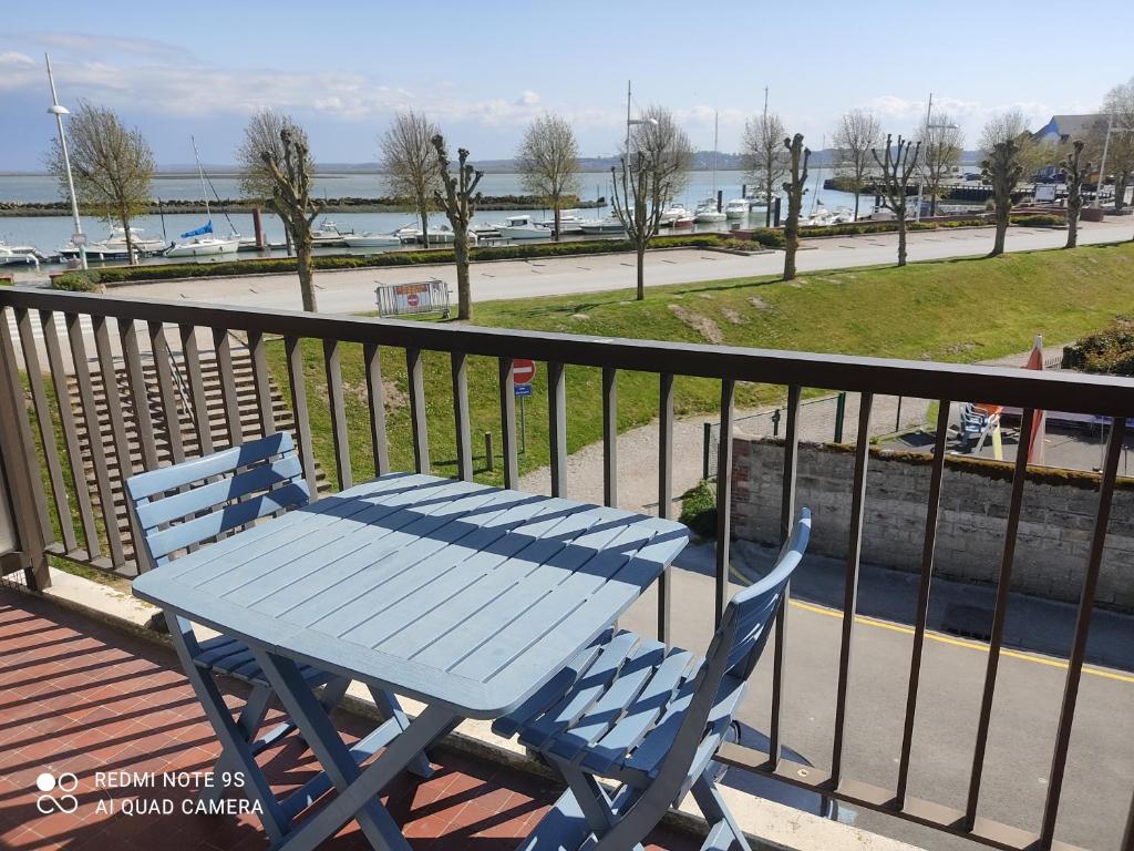 una mesa de picnic azul en un balcón con vistas al agua en Appartement sur le port du Crotoy vue Baie de Somme, en Le Crotoy