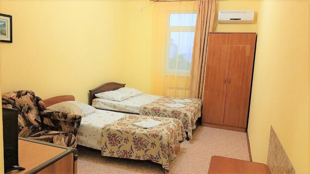 アナパにあるЧастный коттедж "Полинка"のベッド2台、椅子、窓が備わる客室です。