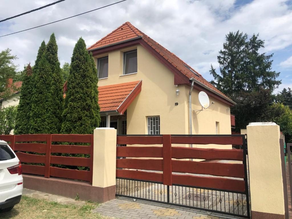 una casa con una valla de madera y un coche blanco en Luxury apartman, en Balatonkenese