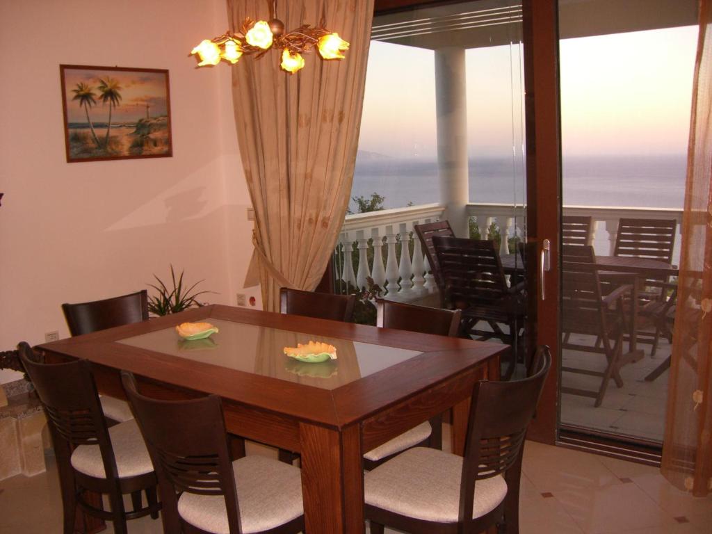 a dining room with a table and chairs and a balcony at Villa Panorama in Lourdata