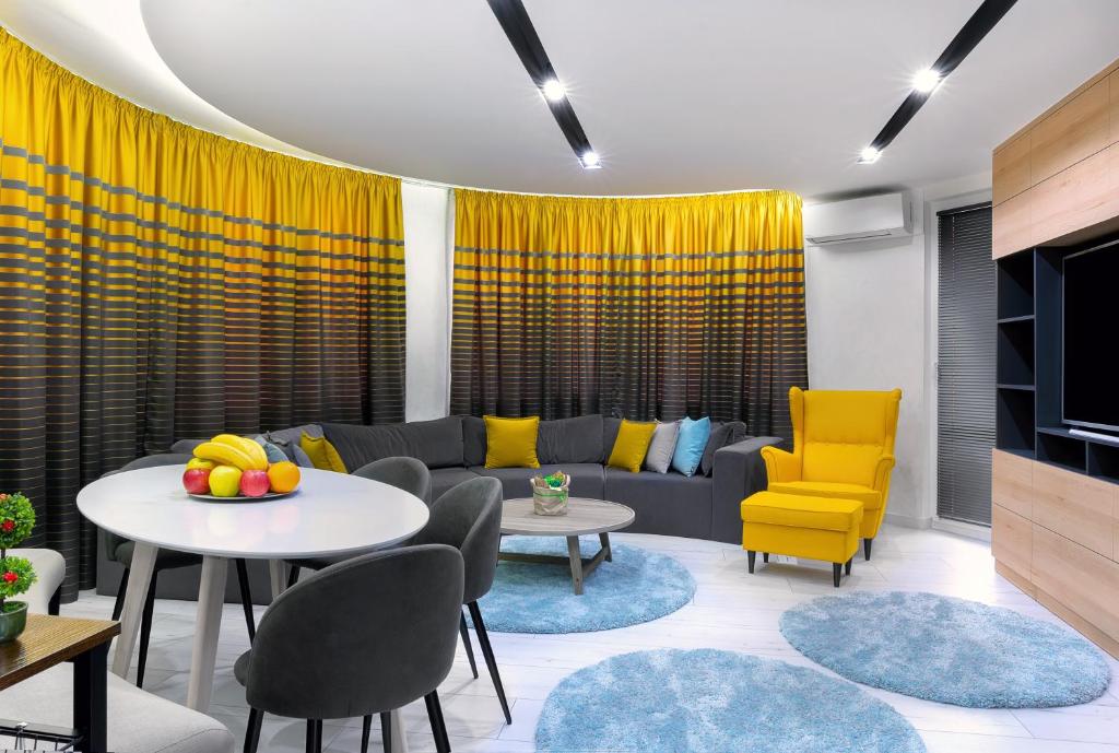 a living room with a couch and a table and yellow chairs at Perla Luxury Apartment in Burgas City