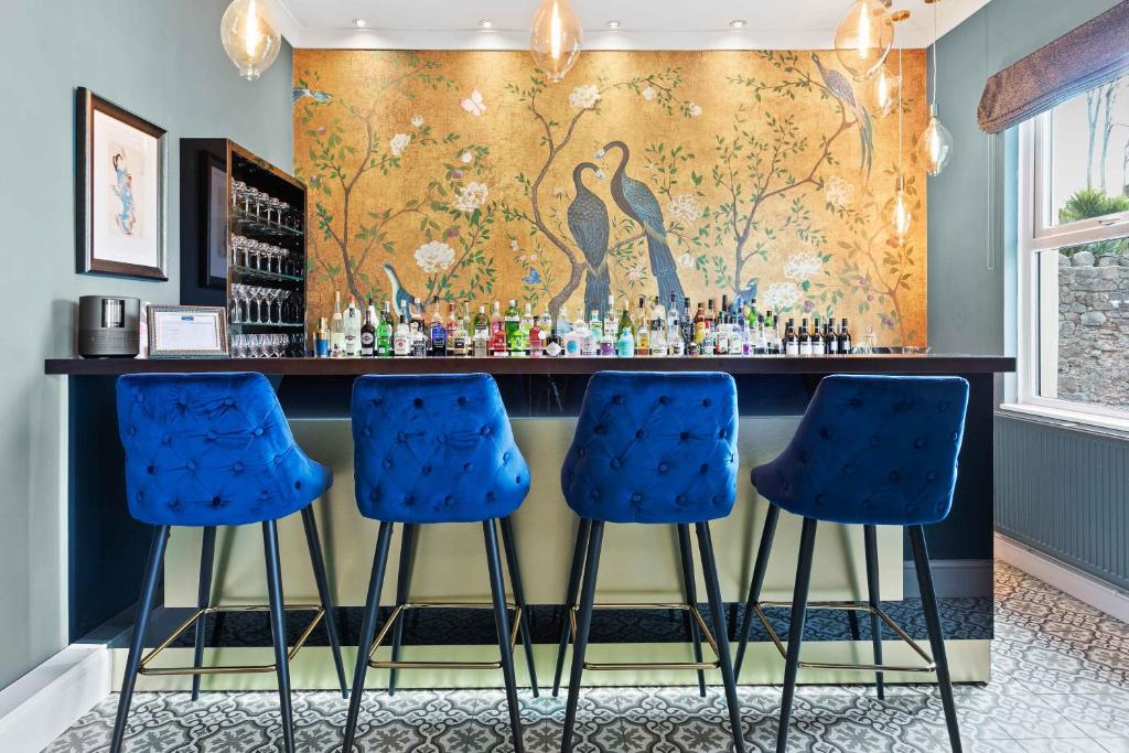 a bar with blue bar stools and a wallpaper at The Torcroft in Torquay