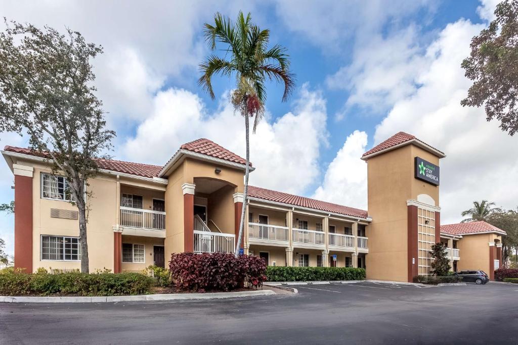 a hotel with a palm tree in front of a parking lot at Extended Stay America Suites - Miami - Airport - Doral in Miami