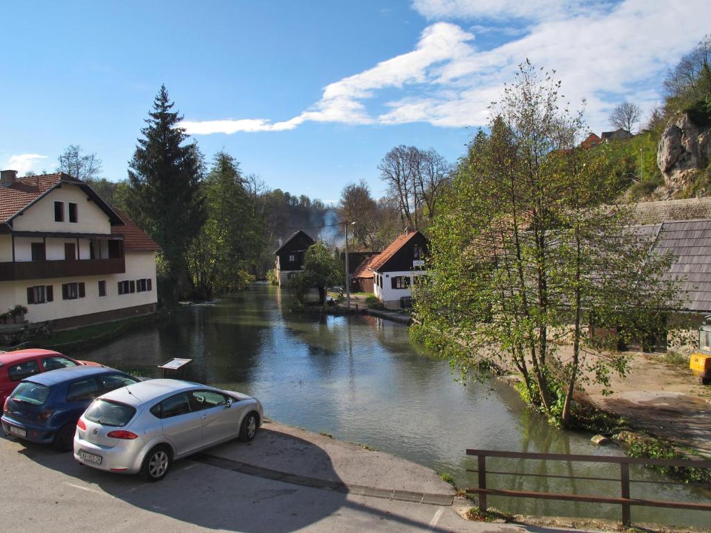 ein Auto parkt auf einem Parkplatz neben einem Fluss in der Unterkunft Rooms Roza in Slunj