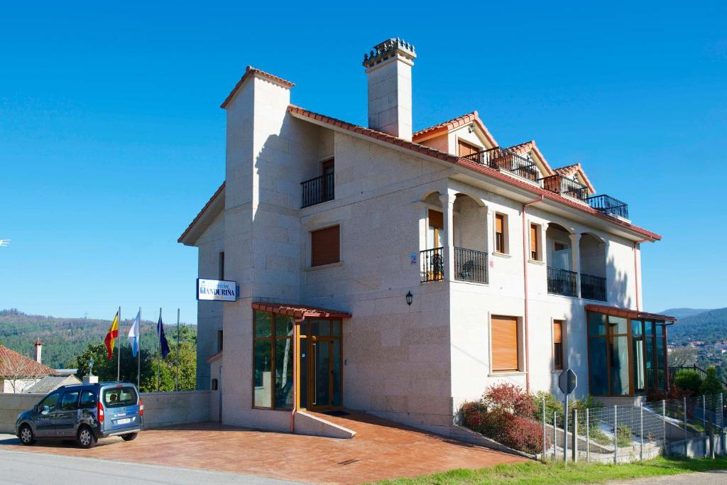 un edificio con un coche aparcado delante de él en VILLA ANDURIÑA, casa con piscina cubierta en Mondariz