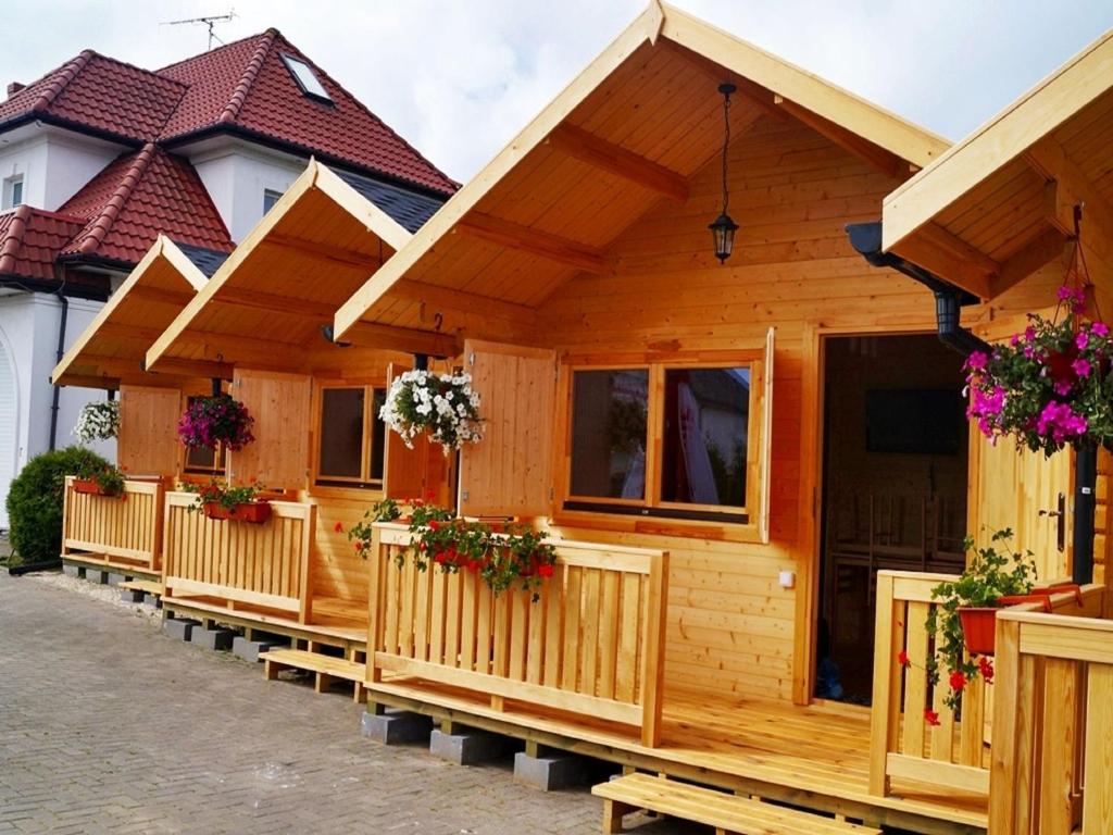 a row of wooden cottages with flowers on them at Cozy Holiday Home in Mielno near Lake in Mielno