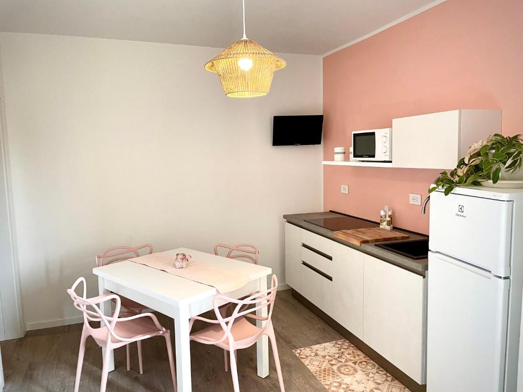 eine kleine Küche mit einem weißen Tisch und rosa Stühlen in der Unterkunft Appartamento Rosa in Pacengo di Lazise