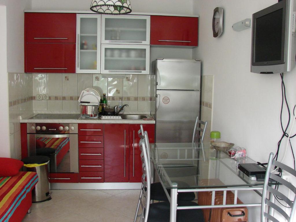 cocina con armarios rojos y nevera de acero inoxidable en Villa Bruna Apartment, en Rab