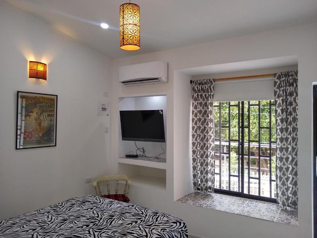 a bedroom with a bed and a window with a television at La Habitación Perfecta in Barranquilla