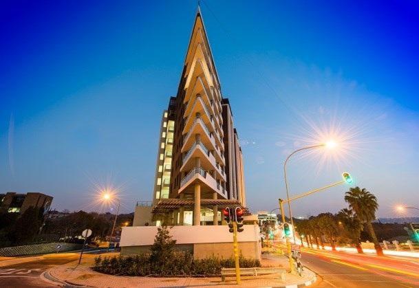 un edificio alto con un campanario en una calle de la ciudad en Stay Ulo at The Apex on Smuts, en Johannesburgo